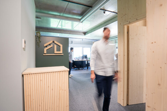 Offener Bürobereich der Deflorin AG mit Holzelementen, modernen Arbeitsplätzen und Mitarbeitenden bei der Arbeit.