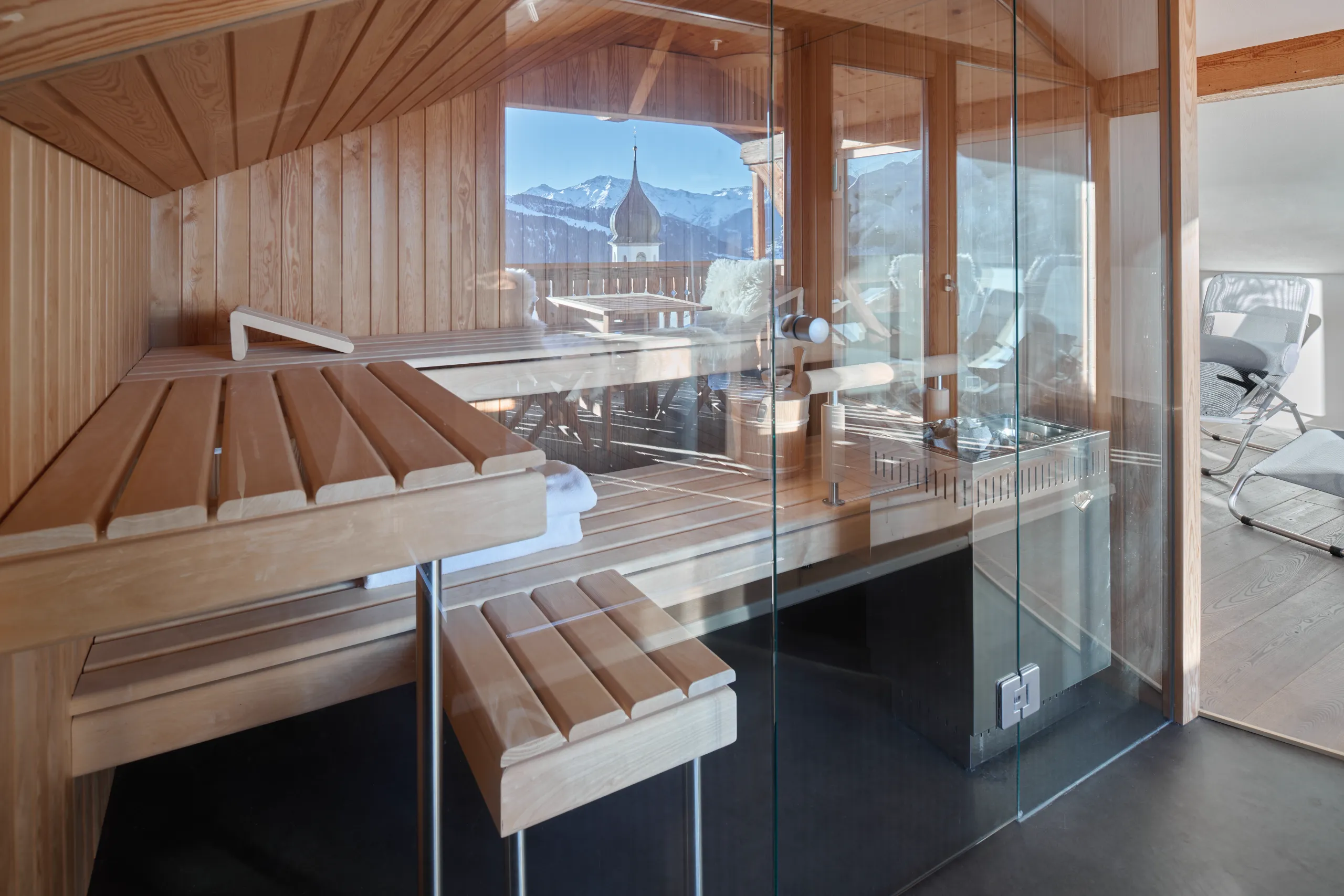 Private Holzsauna im Ferienhaus Siat mit Glasfront, Holzbänken und Blick auf die Berglandschaft.