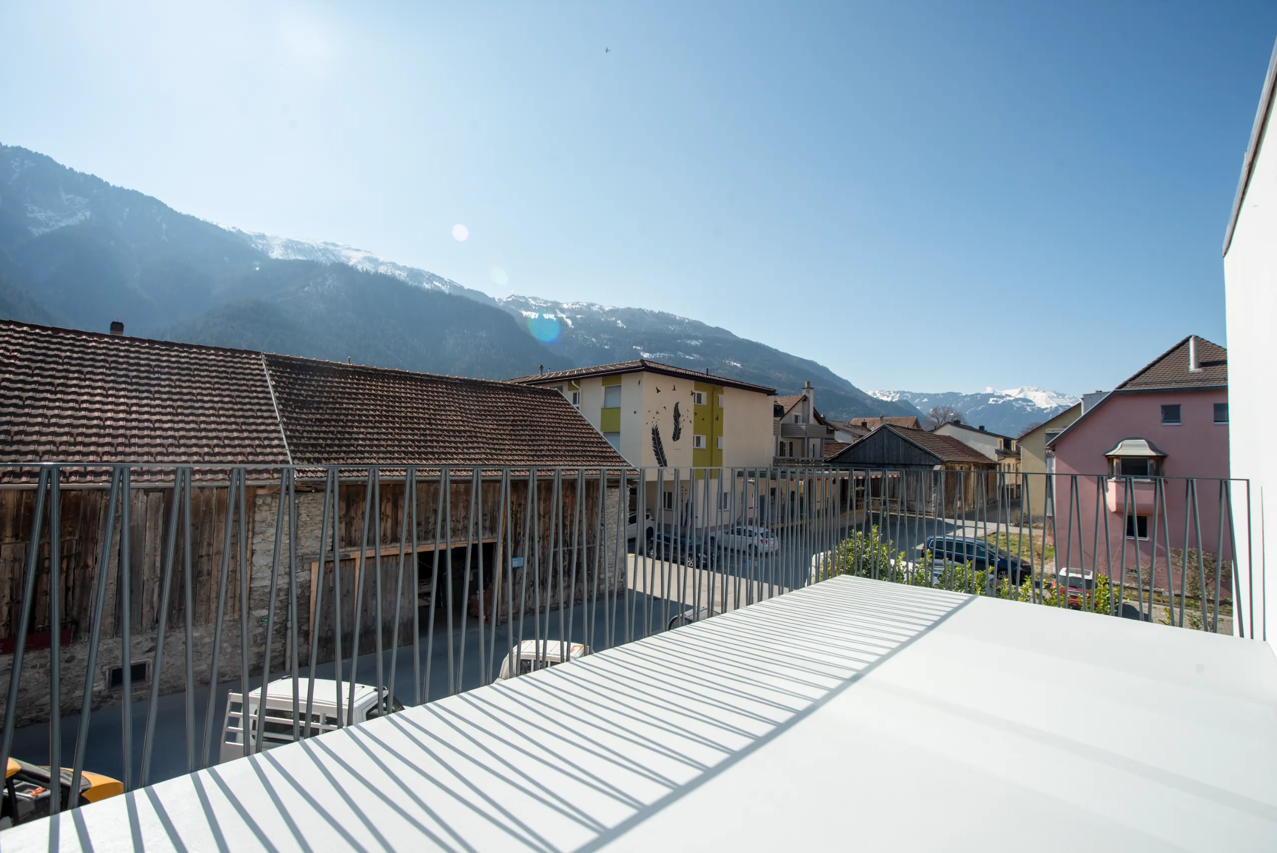 Sonnige Terrasse einer Wohnung in Felsberg mit Metallgeländer und Aussicht auf die Bündner Berglandschaft.