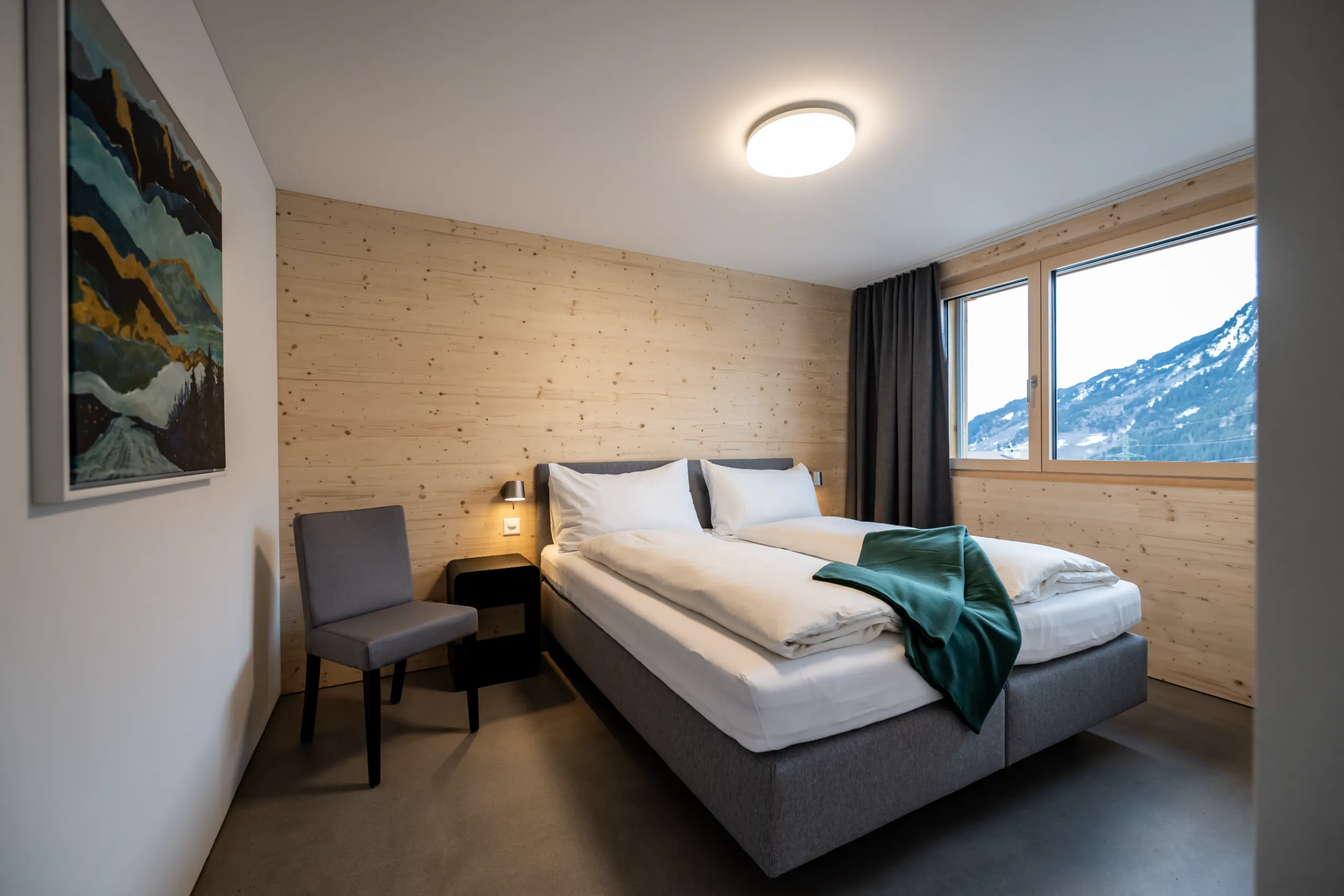 Modernes Schlafzimmer der Residenza Pazzola mit Doppelbett, heller Holzverkleidung und Blick auf die Berge.